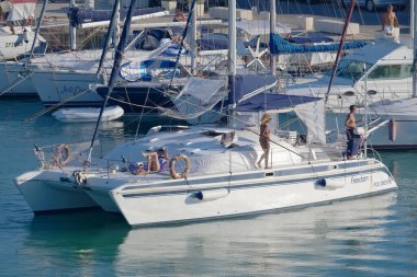 Italy, Sicily, Mediterranean Sea, Marina di Ragusa (Ragusa Province); 27 August 2022, people on a catamaran sailing boat and luxury yachts in the port - EDITORIAL