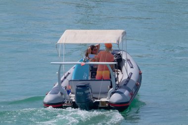 Italy, Sicily, Mediterranean Sea, Marina di Ragusa (Ragusa Province); 4 September 2022, couple on a rubber boat and luxury yachts in the port - EDITORIAL
