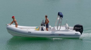 İtalya, Sicilya, Akdeniz, Marina di Ragusa (Ragusa Eyaleti); 9 Eylül 2022, limanda kauçuk bir tekne ve lüks yatlarda bir çift - EDITORIAL