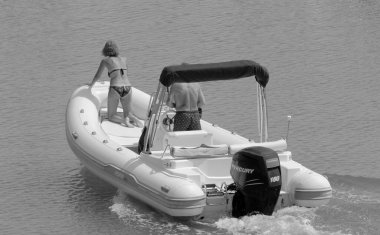 İtalya, Sicilya, Akdeniz, Marina di Ragusa (Ragusa Eyaleti); 9 Eylül 2022, limanda kauçuk bir tekne ve lüks yatlarda bir çift - EDITORIAL