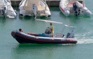 İtalya, Sicilya, Akdeniz, Marina di Ragusa (Ragusa Eyaleti); 10 Eylül 2022, limanda bir kauçuk teknede çift - EDITORIAL