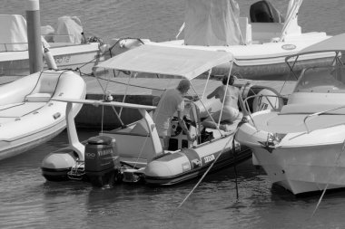 İtalya, Sicilya, Akdeniz, Marina di Ragusa (Ragusa Eyaleti); 10 Eylül 2022, limanda bir kauçuk teknede çift - EDITORIAL