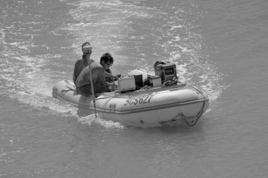 İtalya, Sicilya, Akdeniz, Marina di Ragusa (Ragusa Eyaleti); 11 Eylül 2022, limandaki kauçuk bir teknede erkekler - EDITORIAL