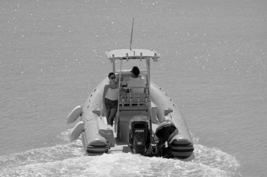 İtalya, Sicilya, Akdeniz, Marina di Ragusa (Ragusa Eyaleti); 11 Eylül 2022, limanda bir kauçuk teknede çift - EDITORIAL