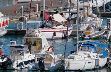 İtalya, Sicilya, Akdeniz, Marina di Ragusa (Ragusa Eyaleti); 11 Eylül 2022, limanda bir yelkenli teknesi ve lüks yatlarda bir çift - EDITORIAL