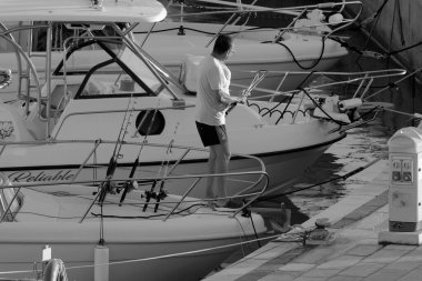 İtalya, Sicilya, Akdeniz, Marina di Ragusa (Ragusa Eyaleti); 11 Eylül 2022, limandaki bir motorlu teknede balıkçı - EDITORIAL