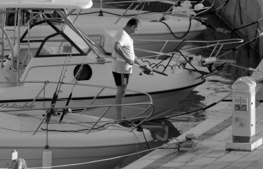 İtalya, Sicilya, Akdeniz, Marina di Ragusa (Ragusa Eyaleti); 11 Eylül 2022, limandaki bir motorlu teknede balıkçı - EDITORIAL