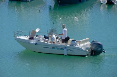 İtalya, Sicilya, Akdeniz, Marina di Ragusa (Ragusa Eyaleti); 12 Eylül 2022, limandaki bir motorlu teknede balıkçı - EDITORIAL