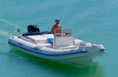 İtalya, Sicilya, Akdeniz, Marina di Ragusa (Ragusa Eyaleti); 14 Eylül 2022, limandaki kauçuk bir teknede adam - EDITORIAL