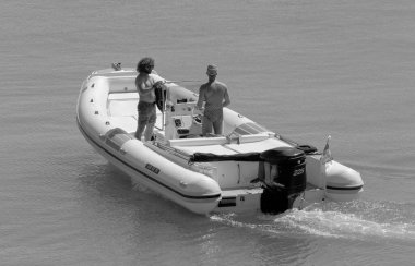 İtalya, Sicilya, Akdeniz, Marina di Ragusa (Ragusa Eyaleti); 14 Eylül 2022, limandaki kauçuk bir teknede erkekler - EDITORIAL