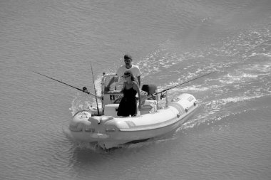 İtalya, Sicilya, Akdeniz, Marina di Ragusa (Ragusa Eyaleti); 14 Eylül 2022, limanda kauçuk bir tekne ve lüks yatlarda bir çift - EDITORIAL