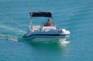 İtalya, Sicilya, Akdeniz, Marina di Ragusa (Ragusa Eyaleti); 14 Eylül 2022, limandaki kauçuk bir teknede adam - EDITORIAL