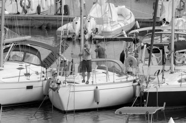 İtalya, Sicilya, Akdeniz, Marina di Ragusa (Ragusa ili); 26 Eylül 2022, limandaki bir yelkenli teknesinde çift - EDITORIAL