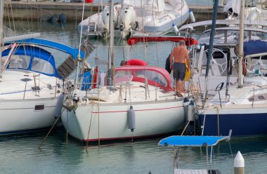 İtalya, Sicilya, Akdeniz, Marina di Ragusa (Ragusa ili); 26 Eylül 2022, limandaki bir yelkenli teknesinde çift - EDITORIAL
