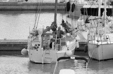 İtalya, Sicilya, Akdeniz, Marina di Ragusa (Ragusa Eyaleti); 30 Eylül 2022, limandaki bir yelkenli teknesinde çift - EDITORIAL