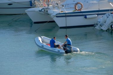 İtalya, Sicilya, Akdeniz, Marina di Ragusa (Ragusa Eyaleti); 24 Ekim 2022, limanda kauçuk bir bot ve lüks yatlarda erkekler - EDITORIAL