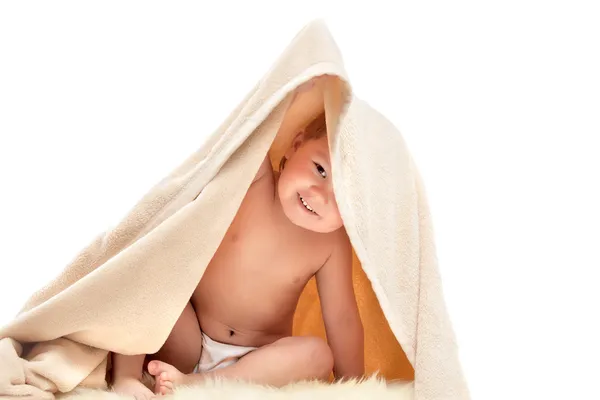 Criança pequena joga sob toalha bege — Fotografia de Stock