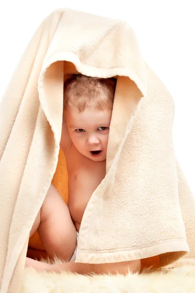 Маленький ребенок играет под бежевым полотенцем — стоковое фото