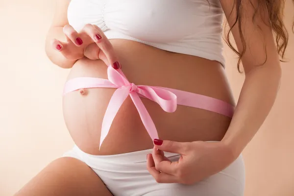 Vientre embarazada con cinta rosa —  Fotos de Stock