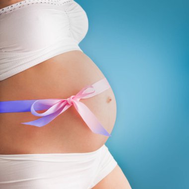 Pregnant pretty belly with colored ribbon. Third trimester.
