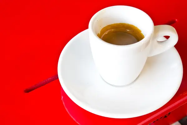 Feketés csésze piros asztalon — Stock Fotó