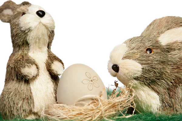 Two ornament rabbits with egg in a nest — Stock Photo, Image