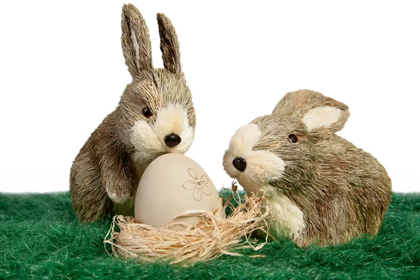Two ornament rabbits with egg in a nest — Stock Photo, Image