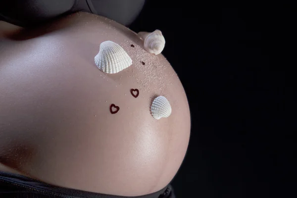 Pregnant belly with decorative seashells on it — Stock Photo, Image