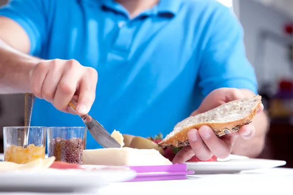 Mannen som smörar en brödskiva wholewheat — Stockfoto