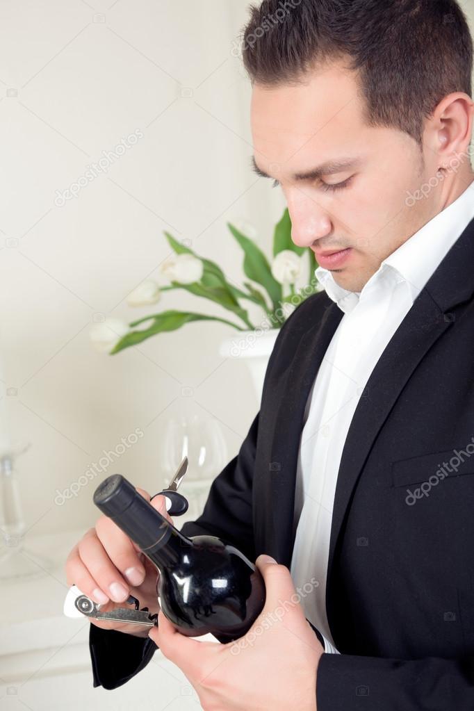Stylish man opening a bottle of wine