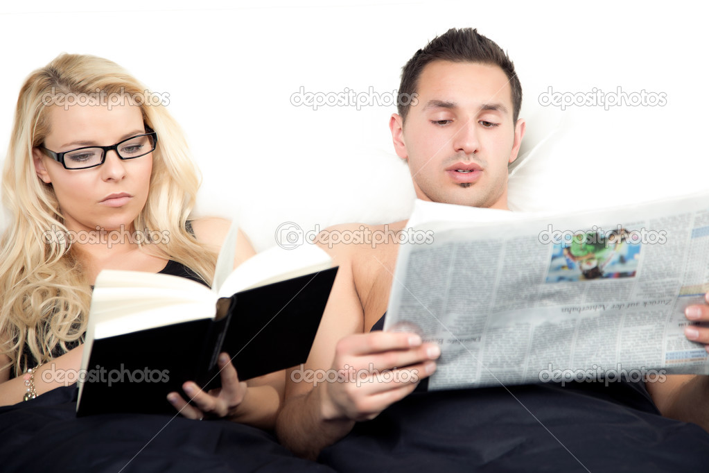 Amicable couple reading in bed together