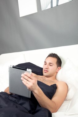 onun tablet üzerinde çalışan yatakta yatan adam