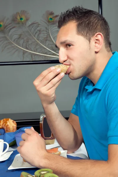 Young man eating breakfast — Stock Photo, Image