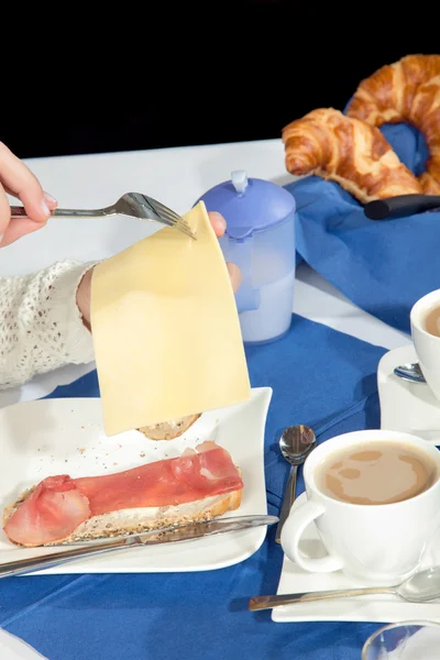 Woman helping herself to sliced cheese — Stock Photo, Image