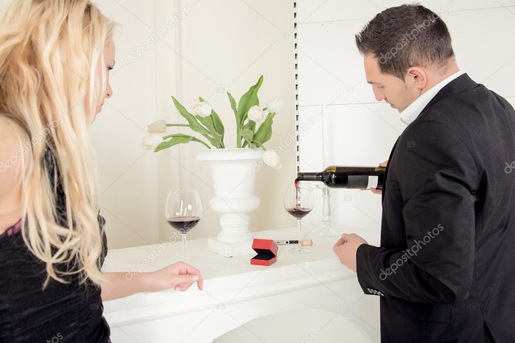 Man pouring red wine with a open ring box