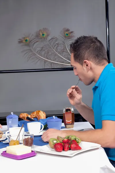 Молодой человек ест континентальный завтрак — стоковое фото