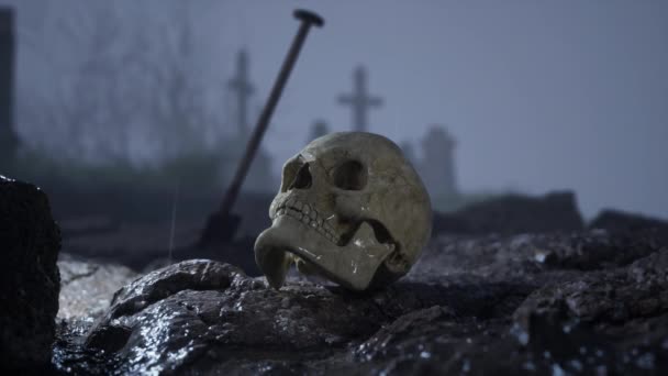 一个人的骷髅躺在墓地的坟墓前 在后面是一个有铁锹的墓穴 — 图库视频影像