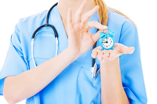 Nurse Holding Toy Alarm Clock Over White Background — Stock Photo, Image