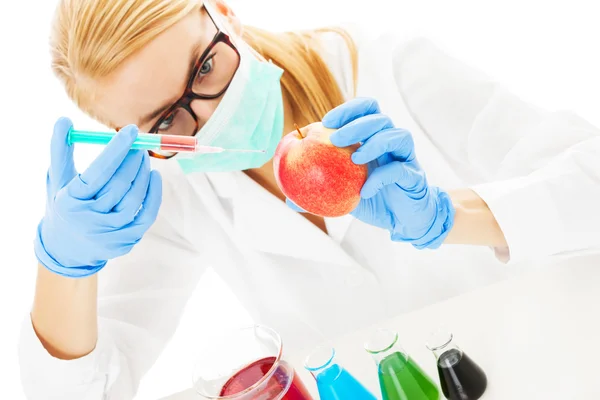 Wetenschapper injecteren van chemische stof in apple aan tafel — Stockfoto