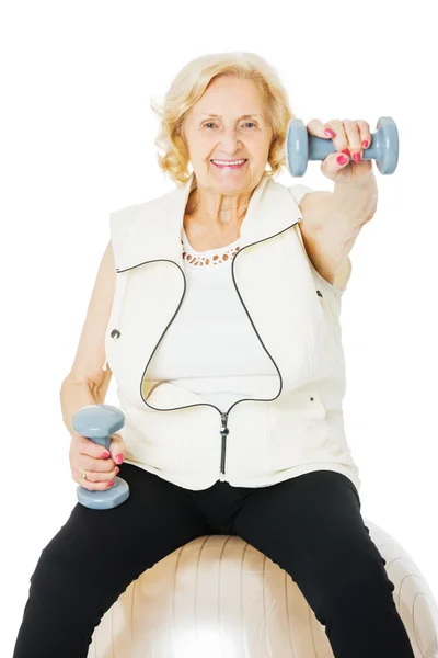 Senior mulher levantando halteres na bola de fitness — Fotografia de Stock