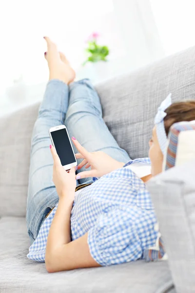 Woman texting on a sofa — Stock Photo, Image