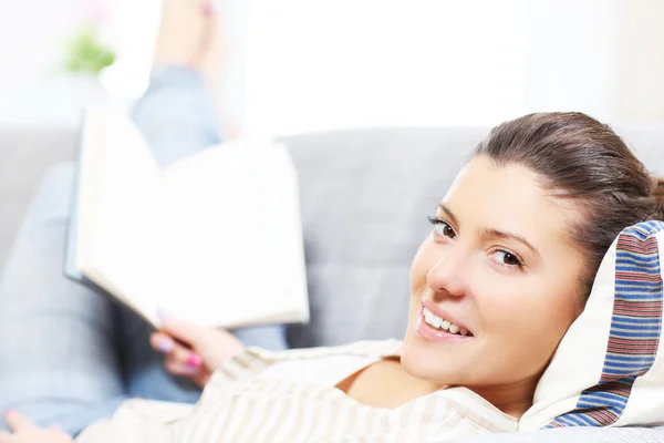 Happy woman reading on a sofa — Stock Photo, Image