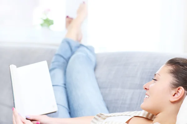 Vrouw leest op een sofa — Stockfoto