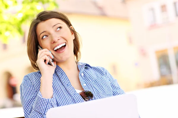 Mujer joven en el teléfono con ordenador portátil — Foto de Stock