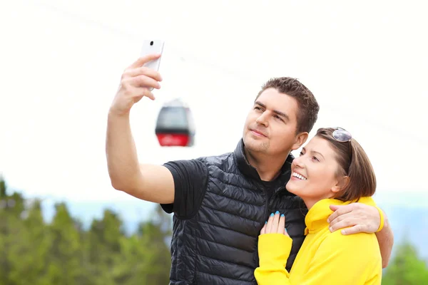 Young couple taking pictures in mountains — 图库照片