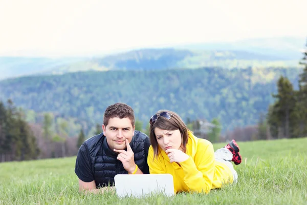 Young couple and laptop in the mountains