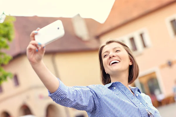 Mulher feliz tomando selfie em uma cidade — Fotografia de Stock