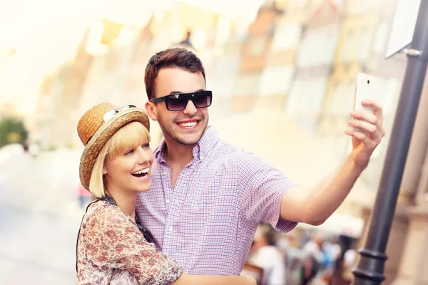 Jovem casal tomando selfie enquanto passeia pela cidade — Fotografia de Stock