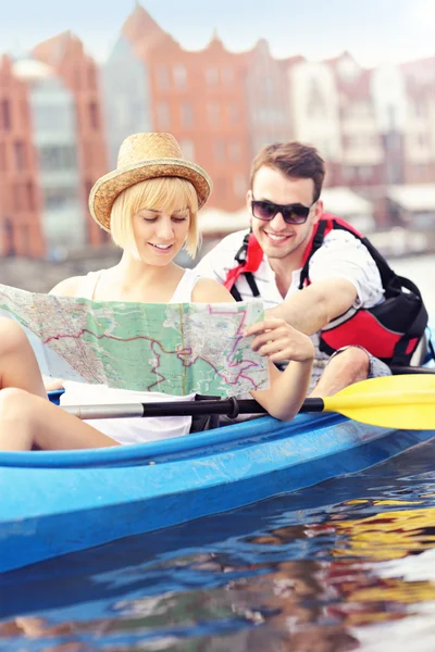 Jóvenes turistas con un mapa en canoa — Foto de Stock