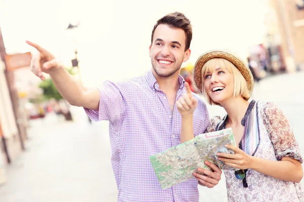 Happy tourists sightseeing the city with a map — Stock Photo, Image